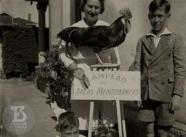 Fotografia de aluno e professora Noêmia Saraiva de Mattos Cruz junto a um Galo "Campeão das ...