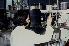 Interior de laboratório, pesquisadora realizando análise cromatográfica de amostras.