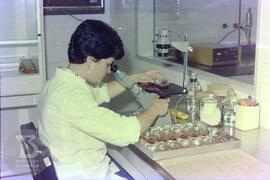 Interior de laboratório, pesquisadora realizando exame das garrafas com cultura de células.